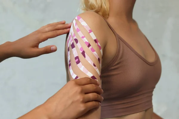 Kolunda ve omzunda Kinesio bandı olan bir kadın. Kinesio terapisi için alçıyla kasların sabitlenmesi..
