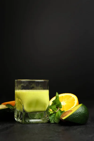 Koyu arkaplanda cam bardakta yeşil meyve püresi. Kereviz, elma, avokado, portakal ve nane. Superfood, detoks, diyet, sağlıklı yiyecekler..