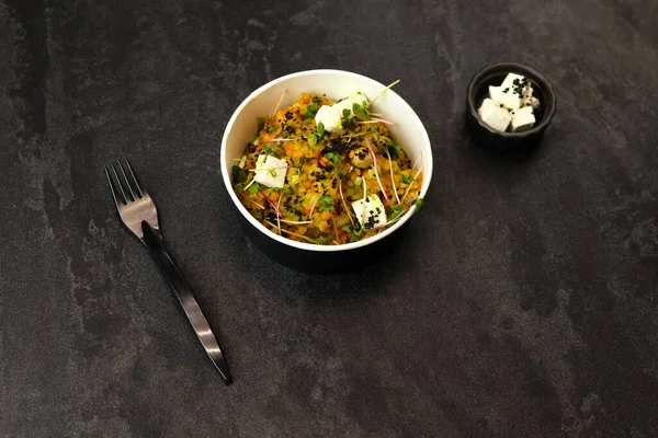 Sağlıklı vejetaryen kasesi, kırmızı mercimek, beyaz peynir ve koyu arka planda plastik çatallı yeşiller. Gıda dağıtım hizmeti ve günlük istihkak kavramı.