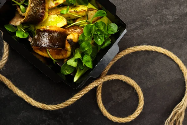 Patates ve marulla pişirilmiş balık uskumrusu. Sağlıklı yemek, restoran yemeği teslimatı. Üst Manzara. Metnin için boş yer. Koyu arkaplan.