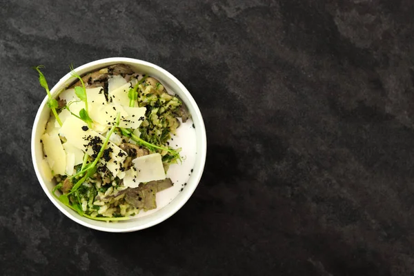 Mantarlı risotto ve siyah arka planda parmesan. Restoran yemeği teslimatı. Üst Manzara. Metin için boş alan. Sağlıklı gıda konsepti.