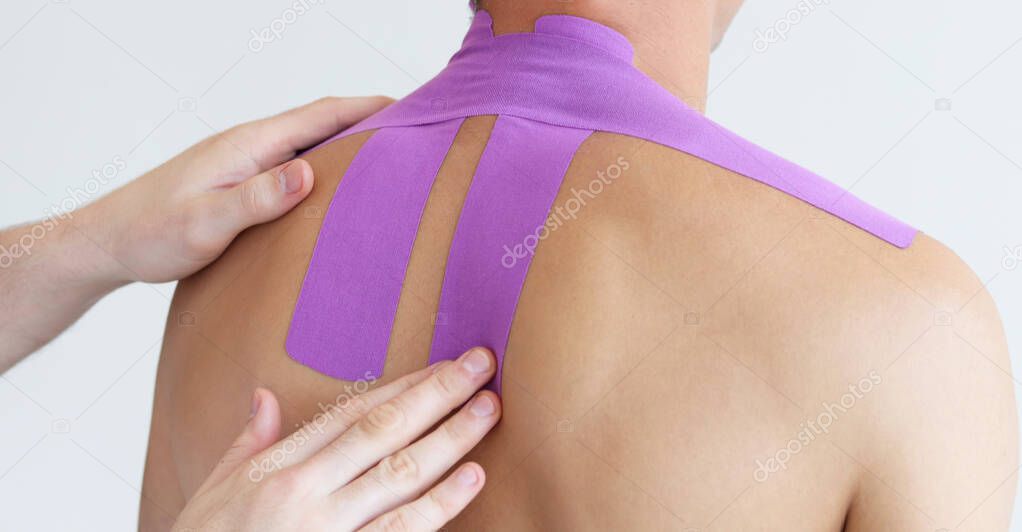 Kinesiology taping. Kinesiology tape on patient neck. Young male athlete on white background. Post traumatic rehabilitation,sport physical therapy, recovery concept, alternative medicine.