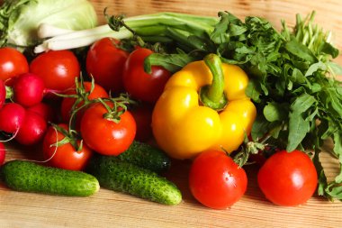 Kırsal bir ahşap masaya yayılmış taze sebze ve otların lezzetli çeşitliliğinin genel manzarası..