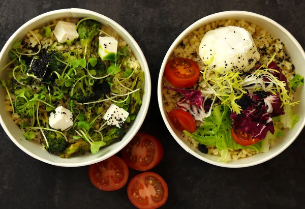 Vegetarian healthy bowls with bulgur, broccoli, greens, feta cheese and poached egg isolated on dark background. Healthy food delivery service and daily ration concept.