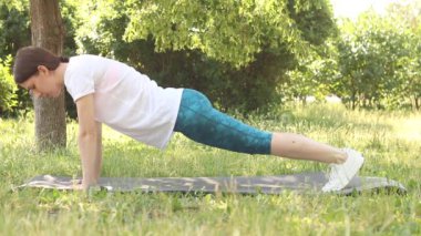 Sportif kadın spor seansı sırasında dışarıda takılıyor. Atletik genç kız kalas egzersizi yapıyor. Spor, eğitim ve sağlık konsepti.