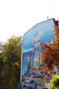 Kyiv, Ukrayna - 30 Ağustos 2019: Sanatsal olarak boyanmış bir evin parçası, gökdelen, kafasında çiçek çelengi olan Ukraynalı bir kız, mavi ev duvarında, duvar resmi. Andrew 'un İnişi.