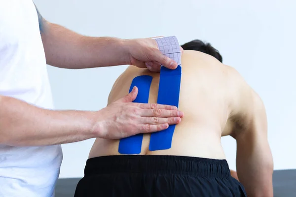 男性患者の腰にキネシオテープを貼った理学療法士 腎臓学 理学療法 リハビリテーションの概念 — ストック写真