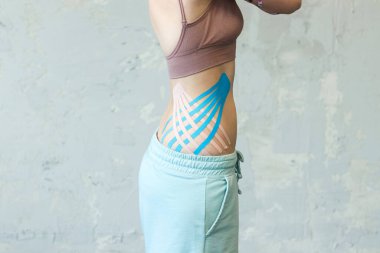 Kozmetoloji kinesio bantları genç kadın beline yakın çekim fotoğrafçılık. Cilt kası dokusunu sıkılaştırmak ve kan dolaşımını iyileştirmek için modern vücut bakımı. Güzellik merkezinde selülit önleme prosedürü