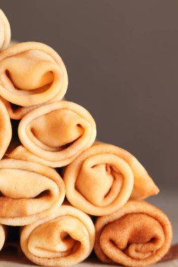 Etle bükülmüş bir yığın krep. Arka planda geleneksel Ukrayna usulü ince Rus krepleri var. Lezzetli sabah kahvaltısı ya da öğle yemeği. Maslenitsa için ev yemeği. Pankart. Görüntüyü kapat.