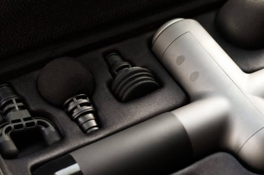 Machine for body massage. Massage percussion device with different of nozzles. Electric massager gun for body massage in a case on a black background.