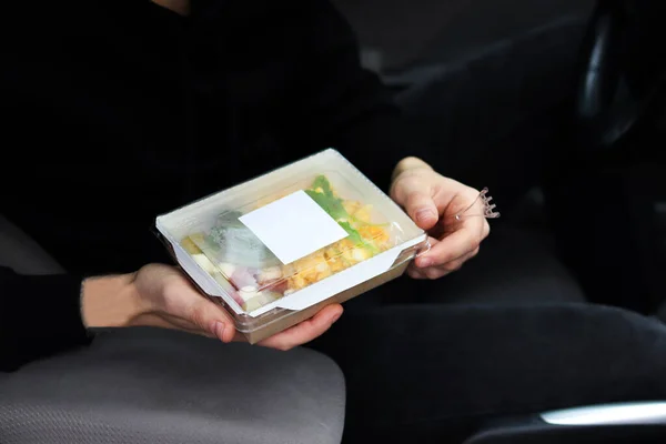 Man unpacking takeaway box with food in the car. Healthy food delivery service and daily ration concept.