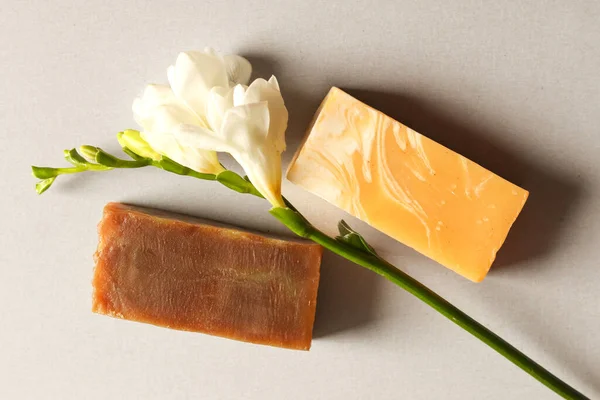 Gri arka planda doğal sabun kalıpları. Frezya çiçeğinin dallı cilt estetiği. Vücut bakımı için güzellik konsepti.