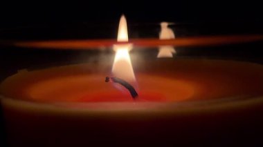 Karanlığın içinde titreyen bir mum alevinin yakın çekim videosu, ılık ışık ve yumuşak bir parıltı, sakin, samimi ve meditasyon havası yaratır..