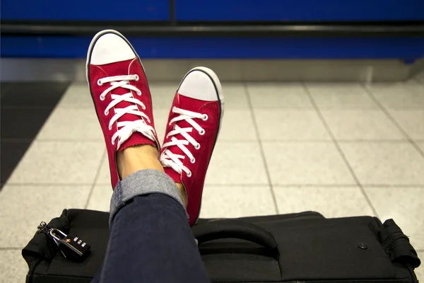 Piedini donna in scarpe da ginnastica rosse sulla valigia Fotografia Stock