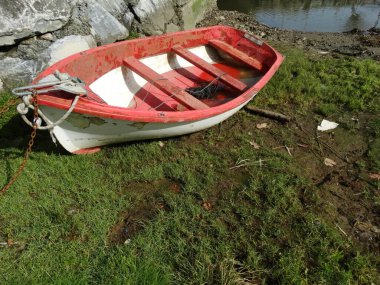 Kırmızı tekne nehir kıyısında terk edilmiş.
