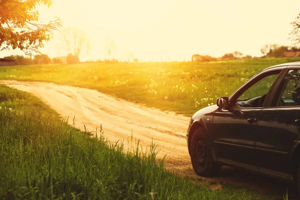Yeşil tarlanın oradaki kır yolunda koyu mavi bir araba. Yüksek kalite fotoğraf
