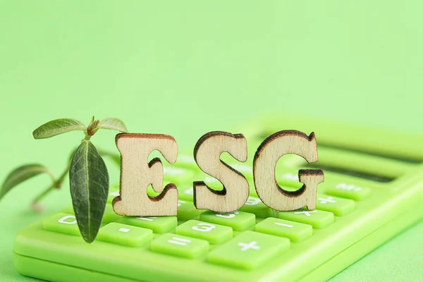Grön miniräknare, träbokstav ESG, färsk planta. Miljö, sociala frågor, bolagsstyrning. Hållbara investeringar. — Stockfoto
