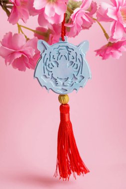2022 Çin Yeni Yılı Madalyası Mavi Kaplan, pembe arka planda pembe çiçekler. İyi talih çiçekleri. Dikey resim