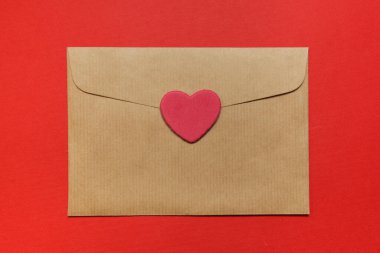 Üst Manzara. Boş zarf, kırmızı arka planda kalp etiketi. Boşluğu kopyala