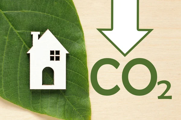Avkolonisering av fastigheter. Minska koldioxidutsläppen och minska kolet. Grönt löv, Hus på trä bakgrund. Hållbar utveckling, miljöskydd — Stockfoto