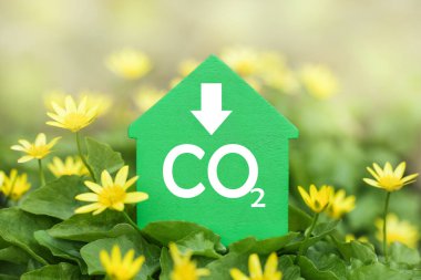Decarbonization of Real Estate. Lower CO2 emissions and reduce carbon. Green House on flower background clipart