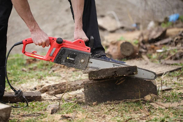 Old Dirty Electric Chainsaw on Wooden logs in garden — Stock Photo, Image