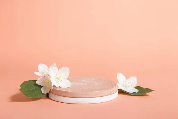 Minimal cosmetic background for product presentation. Cosmetic bottle podium and flower on Pastel coral color background.