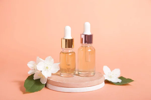 Minimal cosmetic background for product presentation. Cosmetic two bottle oil podium and flower on Pastel coral color background. Mock up