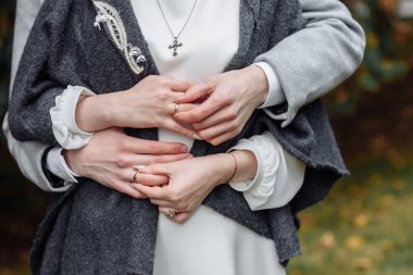 Evlilik yüzükleri takan gençlerin elleri. Düğün günü detayları. Kala çiçekleri. eşler