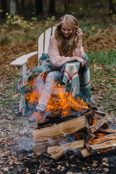 Mujer joven sentada junto al fuego en el hielo caliente de color calentando el calor del fuego pelo largo — Foto de Stock