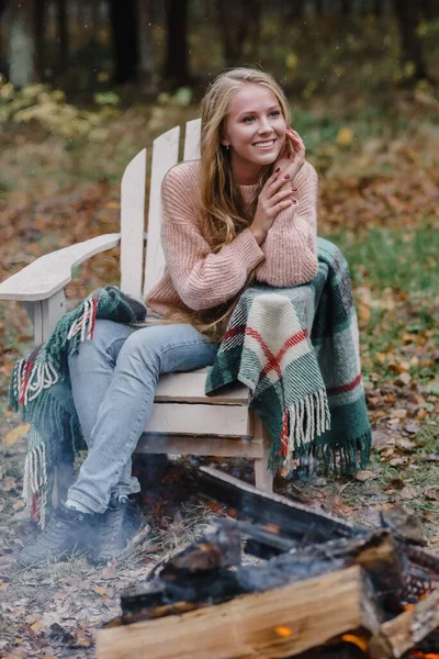 Ateşin yanında oturan genç bir kadın. Renkli, sıcak bir buzun içinde. Uzun saçları ısıtıyor. — Stok fotoğraf