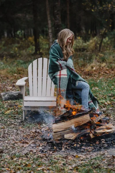 Junge Frau sitzt am Feuer in farbigem, warmem Eis und wärmt lange Haare — Stockfoto