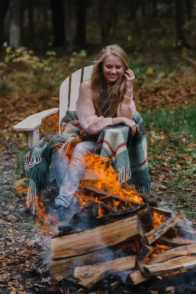 Młoda kobieta siedzi przy kominku w kolorowym ciepłym lodzie rozgrzewając ogień ciepło długie włosy — Zdjęcie stockowe