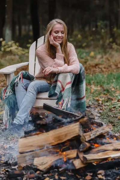 Młoda kobieta siedzi przy kominku w kolorowym ciepłym lodzie rozgrzewając ogień ciepło długie włosy — Zdjęcie stockowe