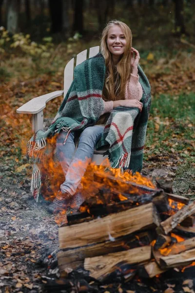 Молодая женщина сидит у огня в цветном теплом льду разогревая огонь тепла длинные волосы — стоковое фото