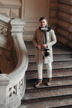 Sokakta yürüyen palto giyen genç bir adam. Şehirdeki modern saç stiline sahip genç sakallı adam.