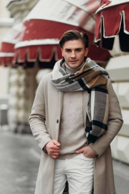 Sokakta yürüyen palto giyen genç bir adam. Şehirdeki modern saç stiline sahip genç sakallı adam.