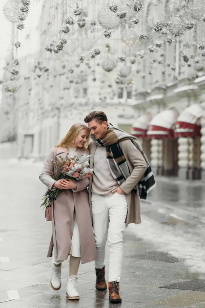 Liefdesverhaal paar liefde jas beige grijs wit boeket van bloemen tederheid gevoelens lopen knuffel date Stockfoto