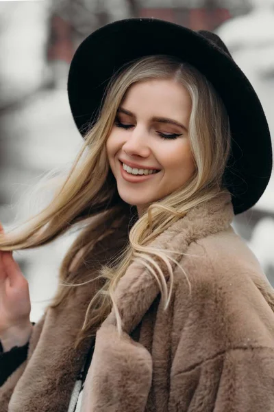 Uśmiechnięta młoda kobieta kapelusz płaszcz zewnątrz kwiaty bukiet żółty radość prezent blondynka model — Zdjęcie stockowe