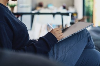 Evdeki dijital tablette stil kalem kullanan bir kadın