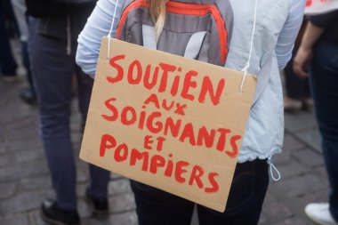 Caddede Fransızca yazılı metinle protesto yapan kadınların kapatılması: soutien aux signets et pompiers, İngilizce: bakıcılara ve itfaiyecilere destek