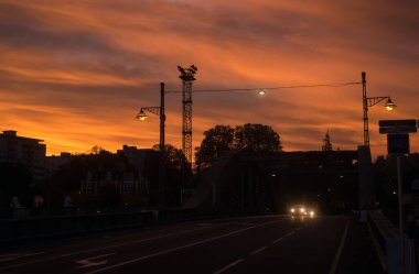 Mulhouse - Fransa - 29 Ekim 2021 - Sabah arkaplanındaki güzel günbatımında sokak lambaları ve metalik köprü siluetinin görüntüsü