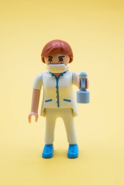 Mulhouse - Fransa - 9 Aralık 2020 - Yüzü maskeli ve sarı arka planda hidroalkolik jeli oyun gezer karaktere yakın çekim