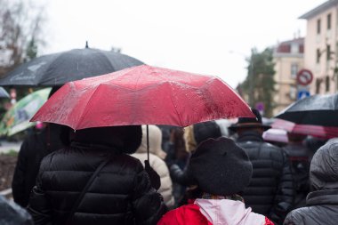 Arka planda şemsiyeyle sokakta yürüyen insanların portresi