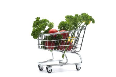 Beyaz arka planda süpermarketin minyatür bir tramvayında taze sebzelerin yakın plan çekimi.