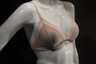 Moda mağazasının kadınlar için sergisinde bej saten sütyenin mankene yakın çekimi.