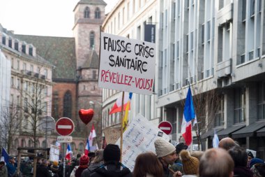 Strasbourg - Fransa - 12 Şubat 2022 - Fransızcada pankartla protesto yapan insanlar: fausse krizse sıhhi, reveillez vous, İngilizce: sahte sağlık krizi, uyanın