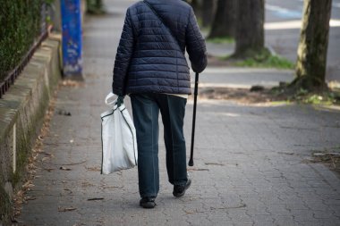 sokakta sopayla arkadan görünüm üzerinde yürüyen yaşlı kadın closeup 
