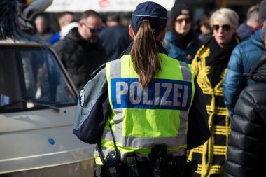 Basel - İsviçre - 7 Mart 2022 - İsviçreli polis kadının sokakta dikilirken arka plandaki portresi