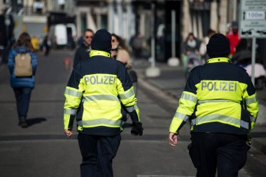Basel - İsviçre - 9 Mart 2022 - İsviçreli kadın polislerin sokakta yürüdüğü arka plandaki portre 